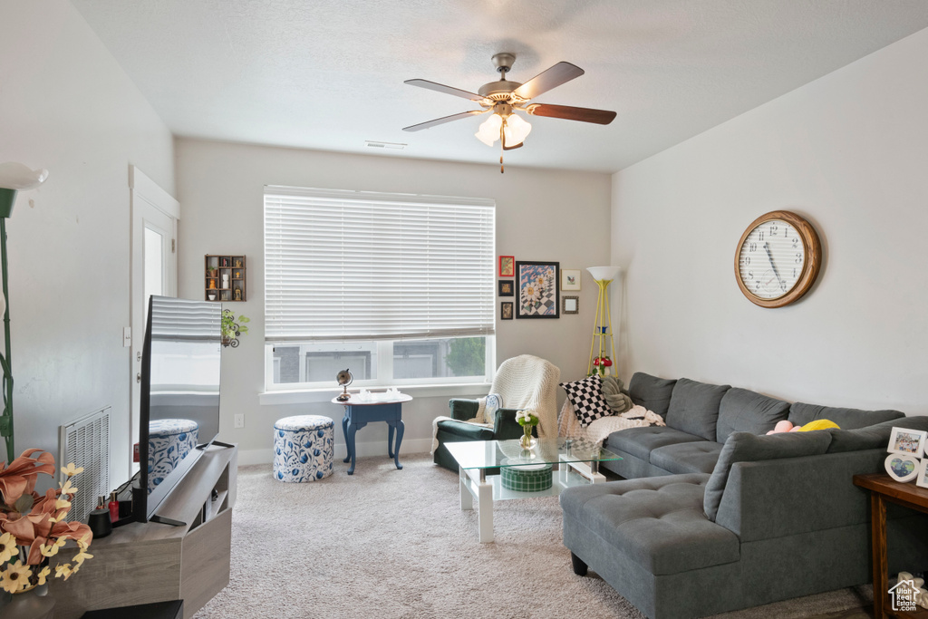 Carpeted living area featuring a ceiling fan and baseboards