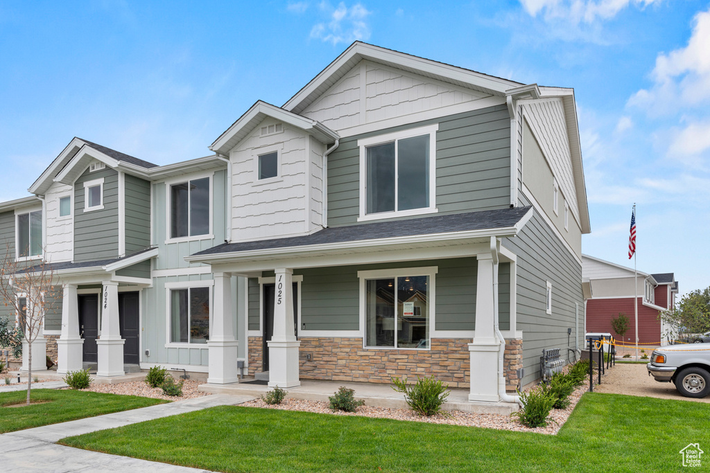 Craftsman inspired home with covered porch, a front yard, and stone siding
