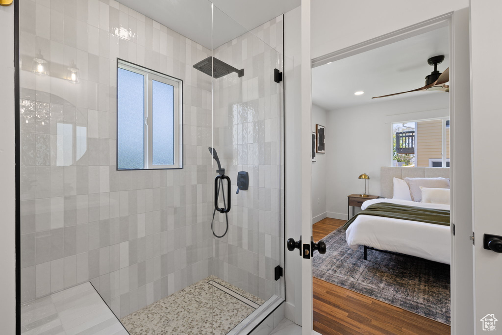 Ensuite bathroom featuring a tile shower, wood finished floors, a ceiling fan, baseboards, and recessed lighting