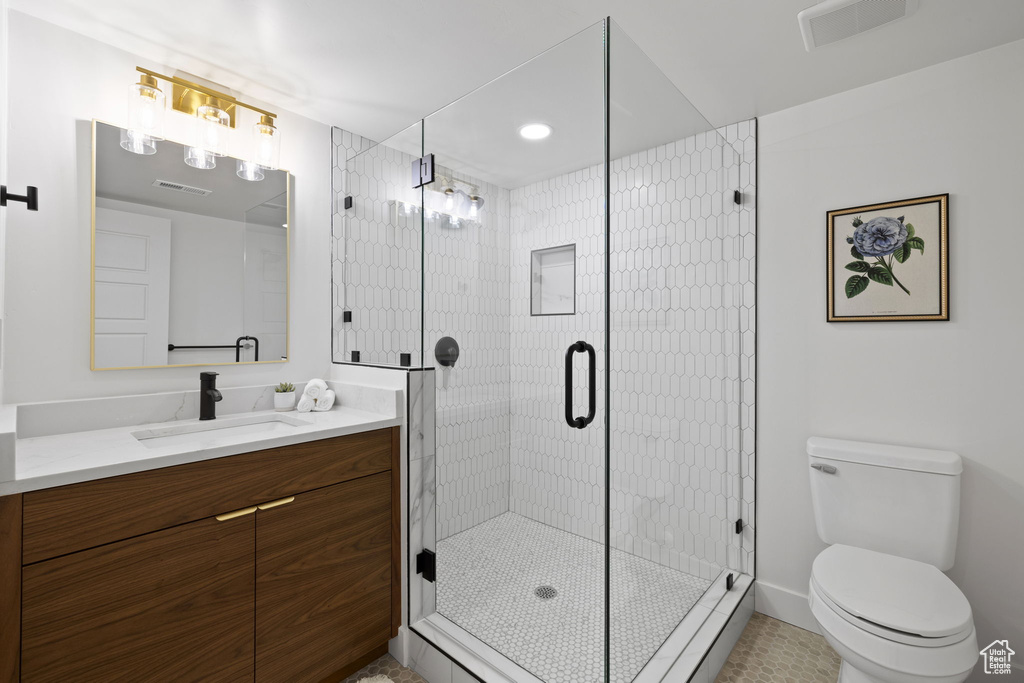 Bathroom with a shower stall, toilet, vanity, and tile patterned floors