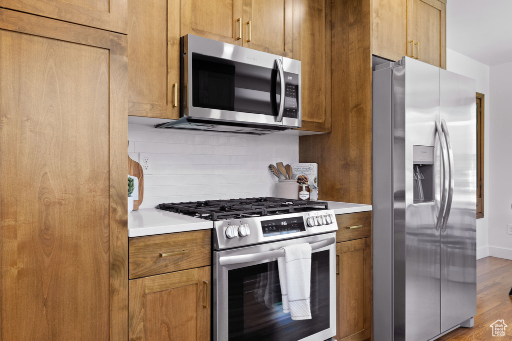 Kitchen featuring stainless steel appliances, tasteful backsplash, light countertops, and light wood finished floors
