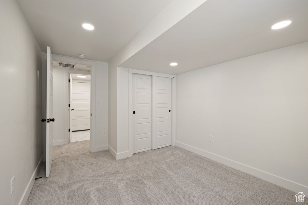 Unfurnished bedroom with light carpet, baseboards, recessed lighting, and a closet