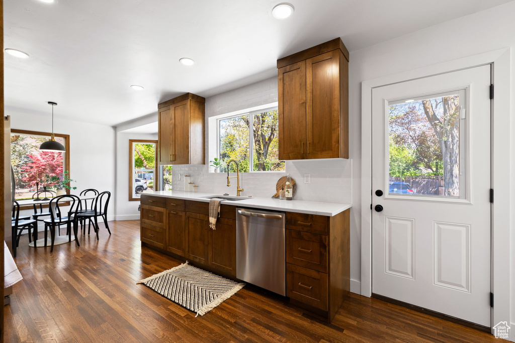 Kitchen featuring stainless steel dishwasher, a sink, light countertops, decorative backsplash, and recessed lighting