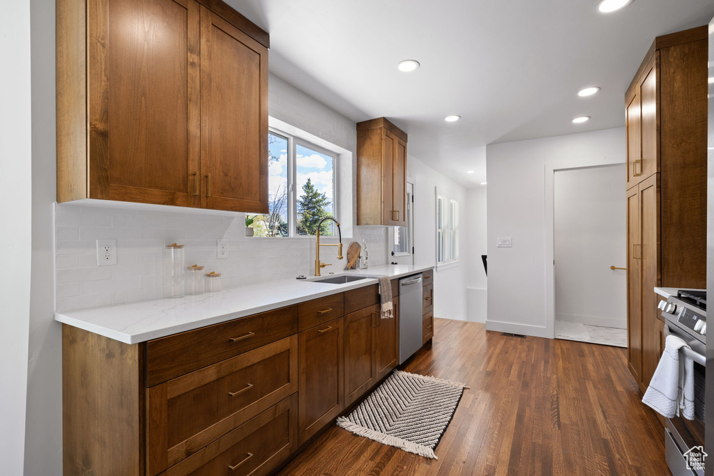 Kitchen featuring stainless steel appliances, tasteful backsplash, recessed lighting, dark wood finished floors, and a sink