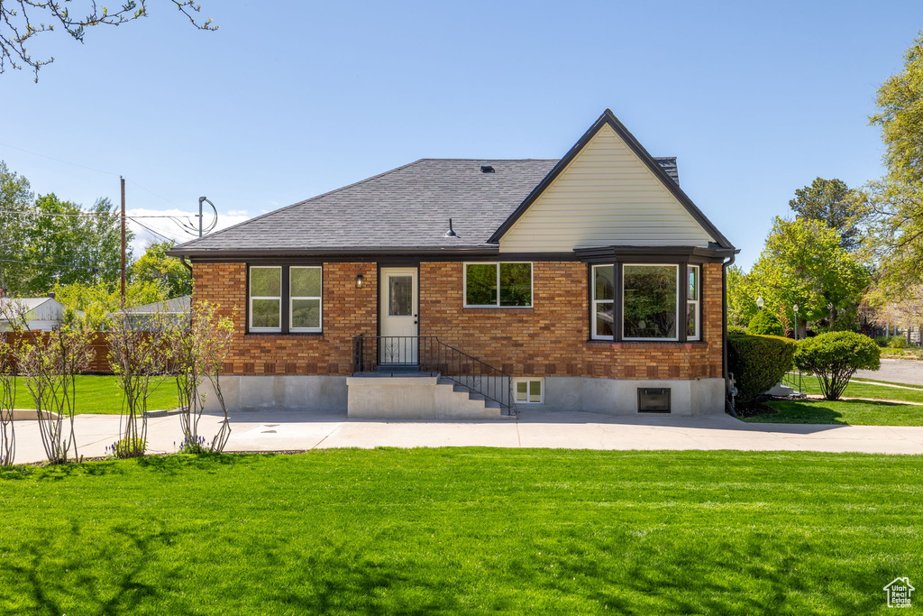 Rear view of house featuring a lawn, brick siding, and a shingled roof
