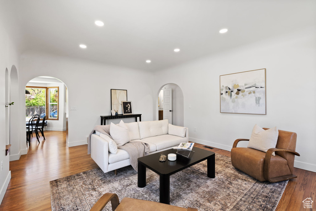 Living room featuring arched walkways, wood finished floors, recessed lighting, and baseboards