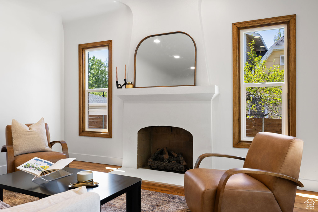 Living area with a fireplace with raised hearth, wood finished floors, and baseboards