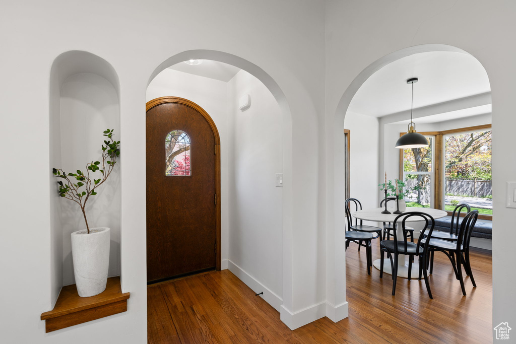 Foyer entrance with wood finished floors, arched walkways, and baseboards