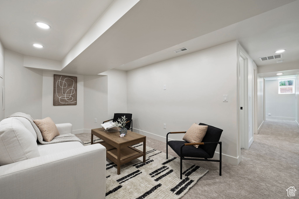 Living area with light colored carpet, baseboards, and recessed lighting