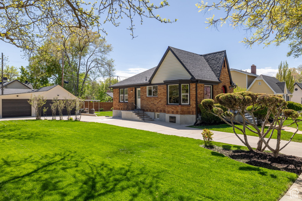View of side of property featuring brick siding, a lawn, and roof with shingles