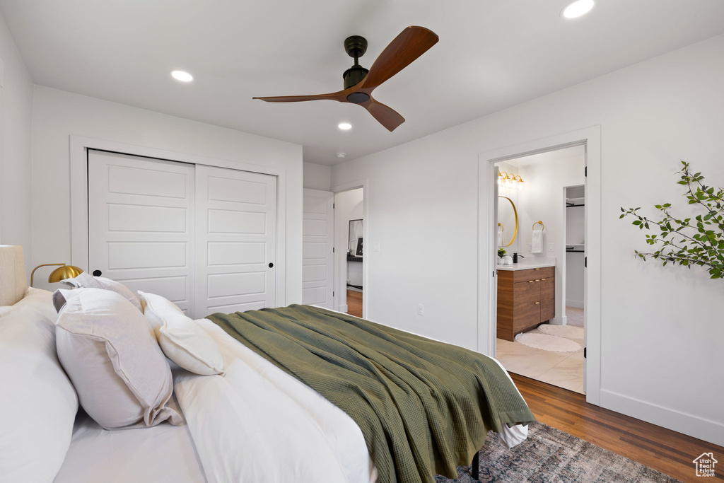 Bedroom with a closet, wood finished floors, recessed lighting, baseboards, and ensuite bathroom