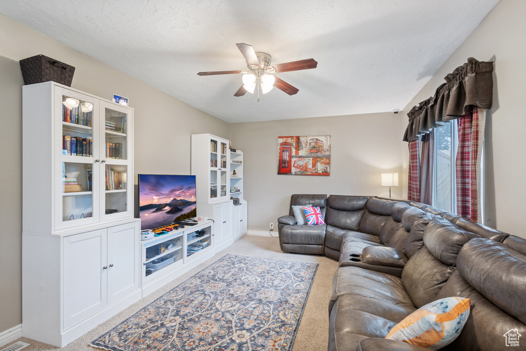 Living area featuring light carpet, ceiling fan, and baseboards