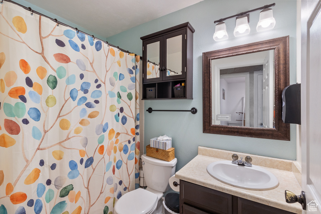 Bathroom featuring toilet, vanity, and a shower with curtain