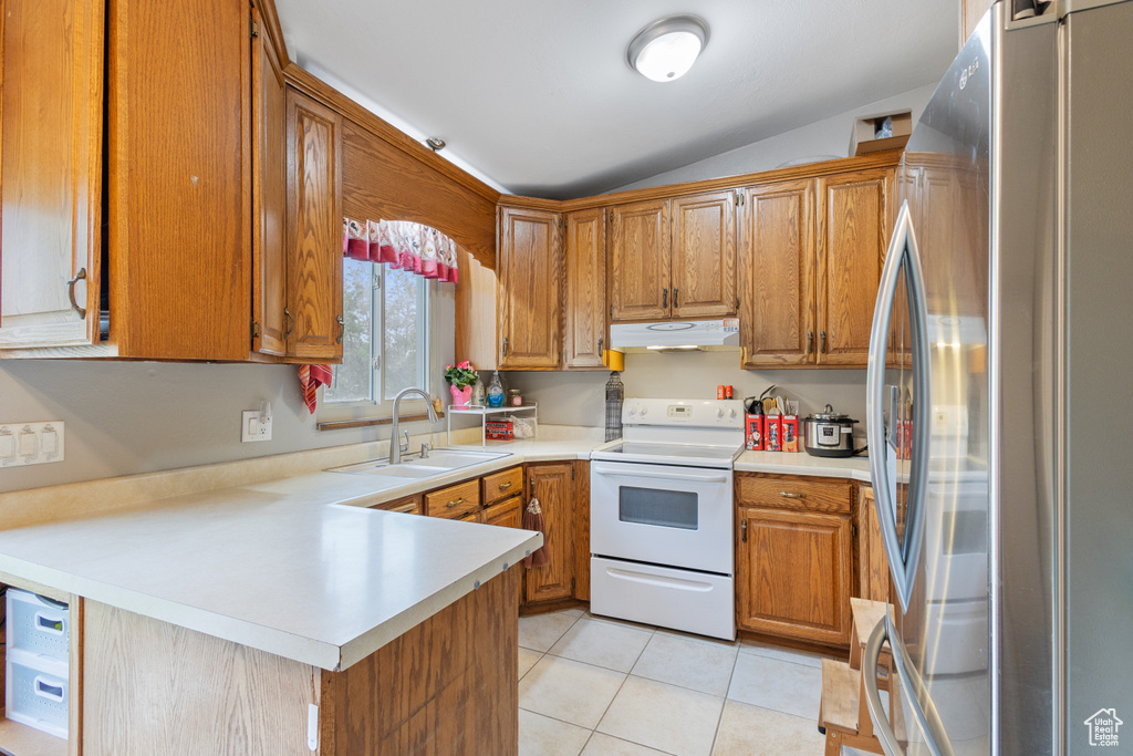 Kitchen with freestanding refrigerator, white range with electric cooktop, under cabinet range hood, lofted ceiling, and a peninsula