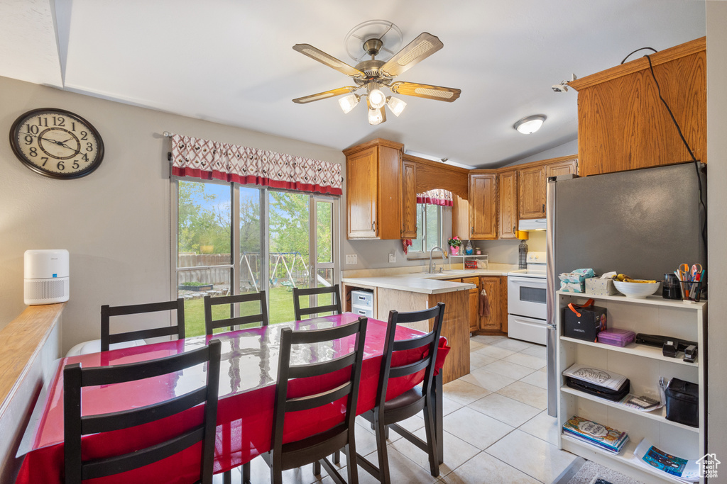 Kitchen with white electric range, light countertops, ceiling fan, light tile patterned floors, and under cabinet range hood
