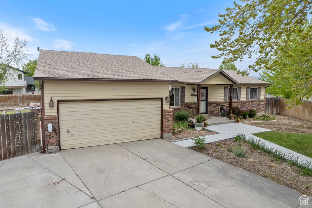 Ranch-style home featuring brick siding, an attached garage, driveway, and roof with shingles