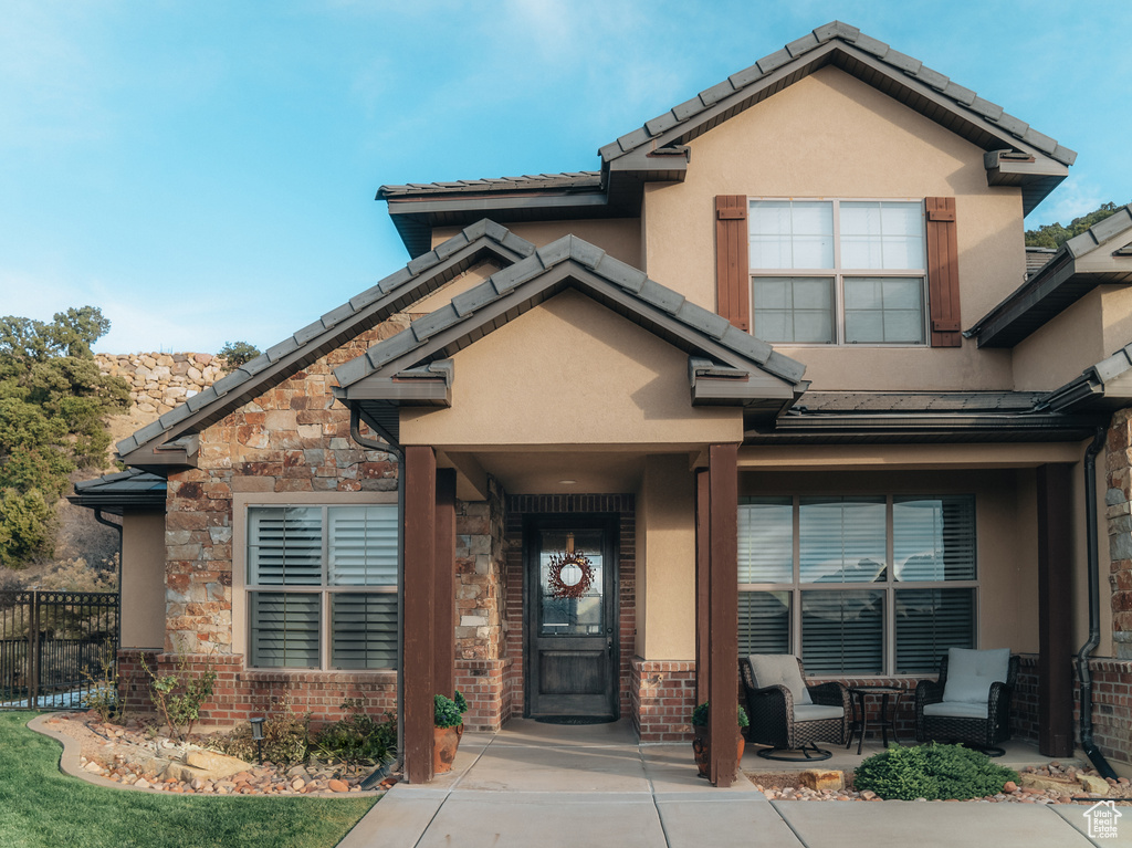 Craftsman-style house featuring stucco siding, fence, stone siding, and a tiled roof