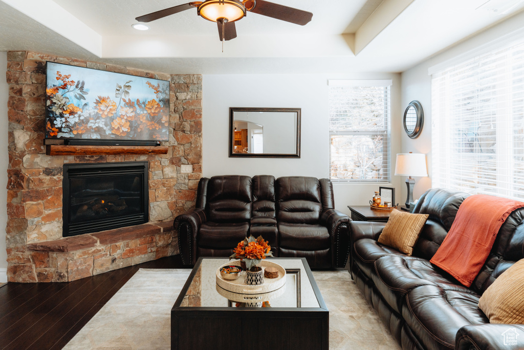 Living area with ceiling fan, a fireplace, light wood-type flooring, a tray ceiling, and recessed lighting