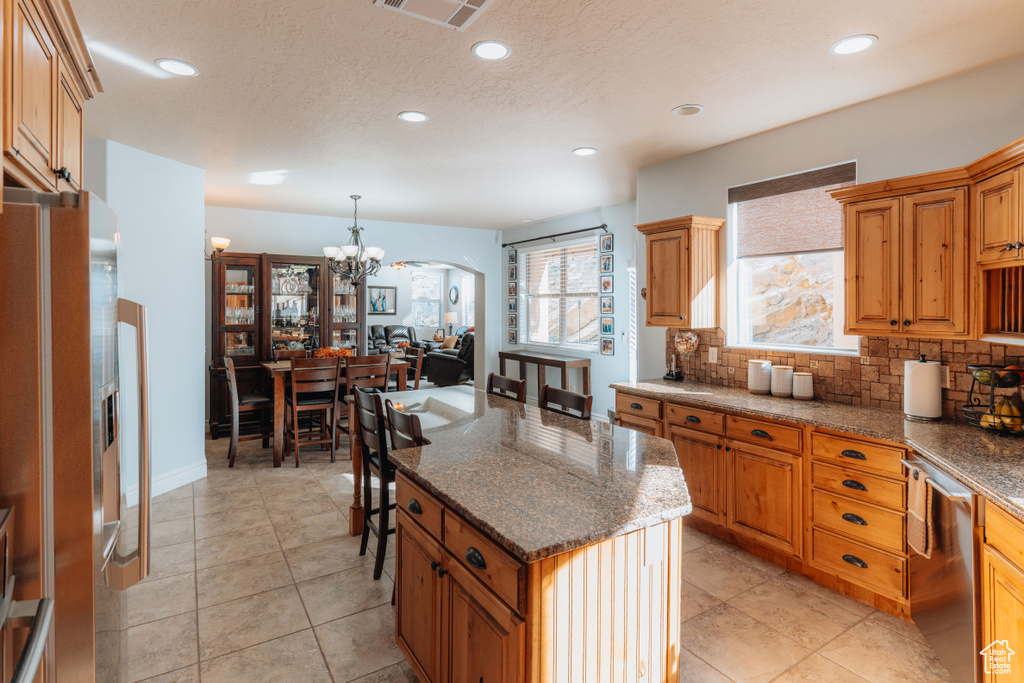 Kitchen with appliances with stainless steel finishes, a chandelier, backsplash, recessed lighting, and arched walkways