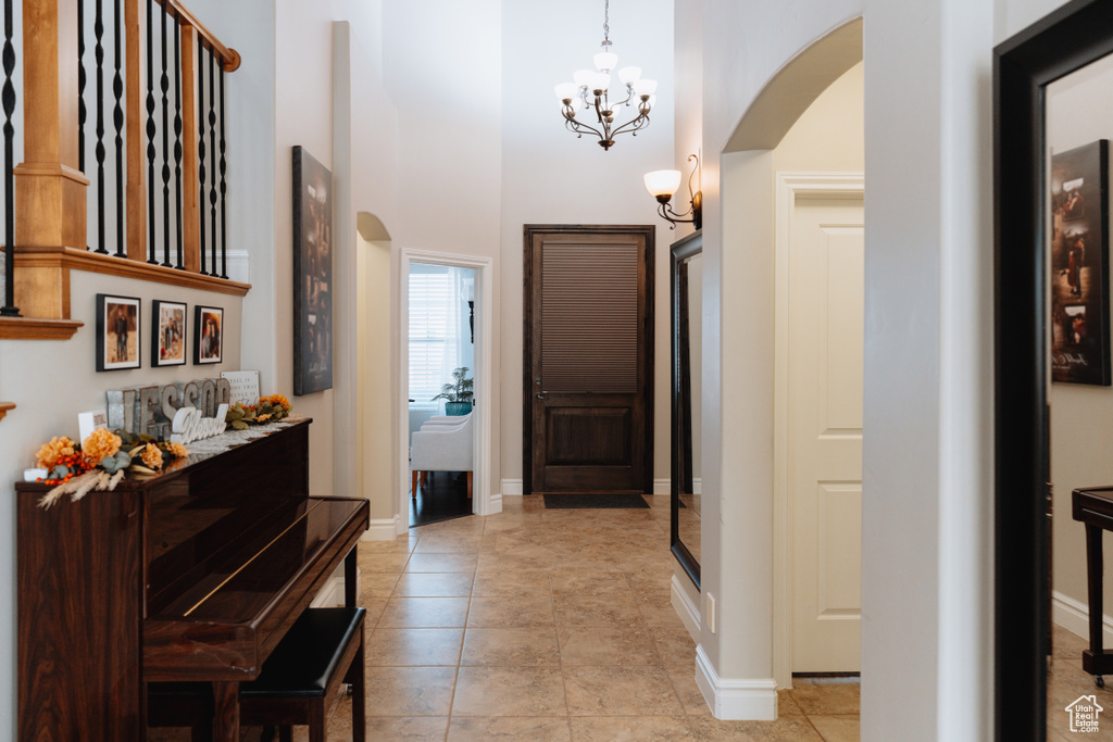 Foyer with arched walkways, a high ceiling, a chandelier, and baseboards