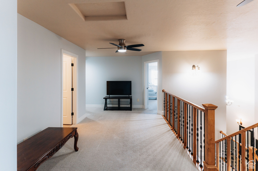 Hall featuring attic access, an upstairs landing, light colored carpet, and baseboards