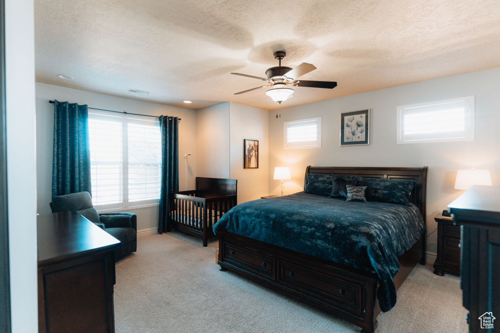 Bedroom with light colored carpet, baseboards, a ceiling fan, and a textured ceiling
