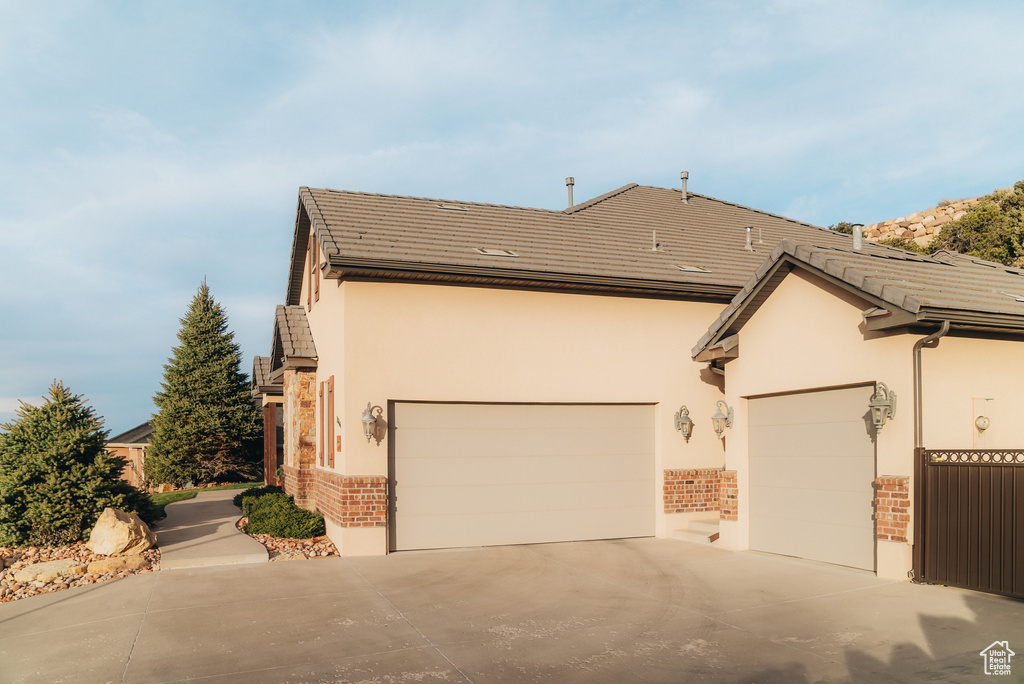 View of home's exterior featuring brick siding, concrete driveway, stucco siding, and an attached garage