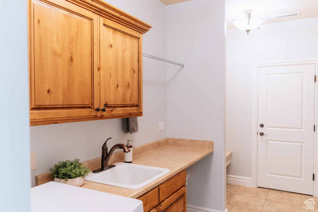 Laundry area with cabinet space, light tile patterned floors, and baseboards