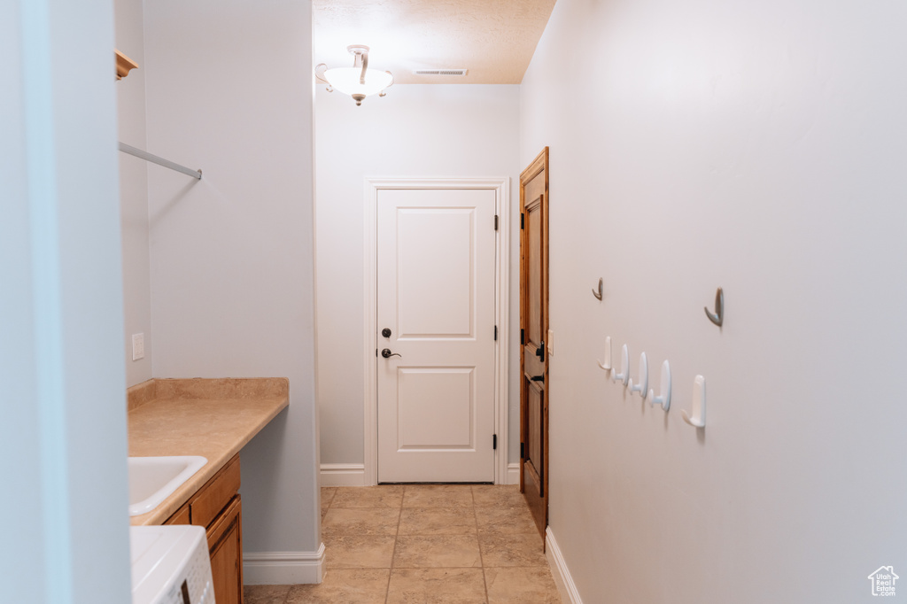 Washroom featuring washer / clothes dryer, baseboards, a sink, and light tile patterned floors