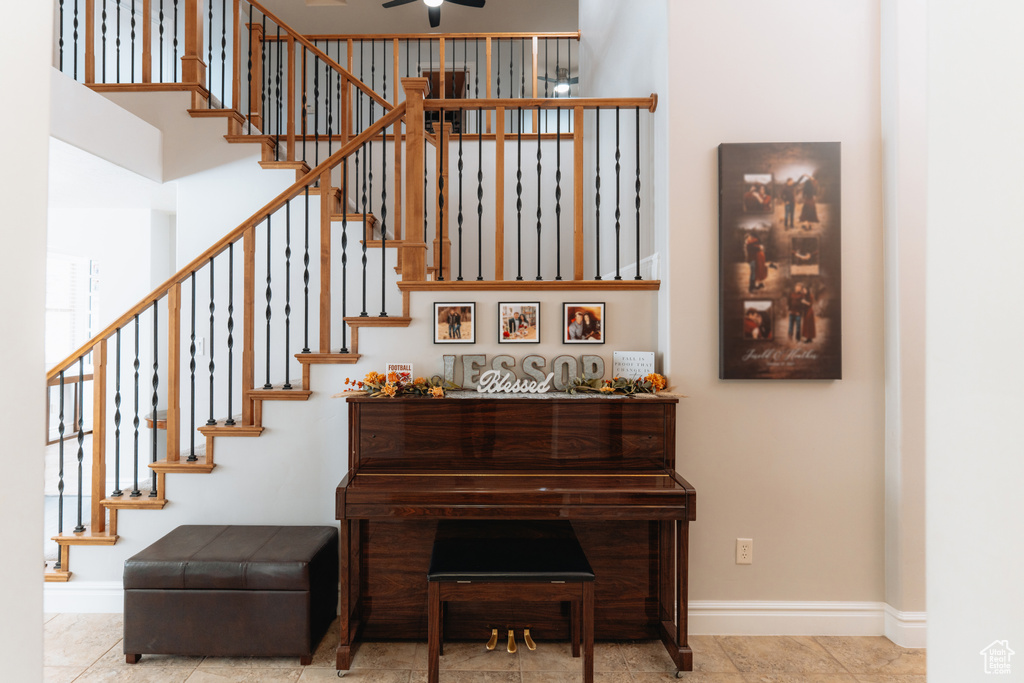 Stairway featuring baseboards, ceiling fan, and a towering ceiling