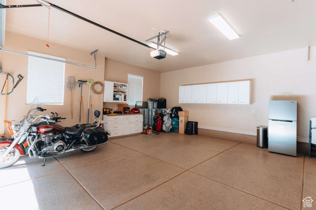 Garage featuring freestanding refrigerator, a garage door opener, and baseboards