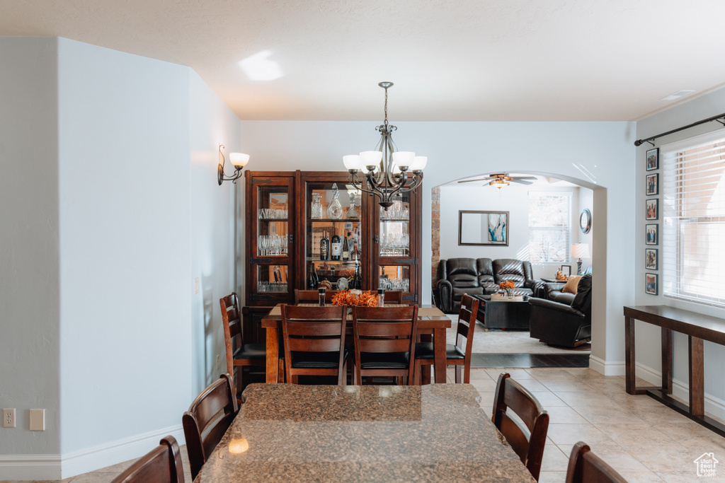 Dining space featuring arched walkways, light tile patterned floors, a chandelier, and baseboards