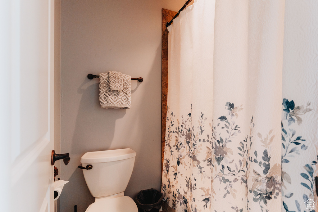 Full bath with toilet and a shower with curtain