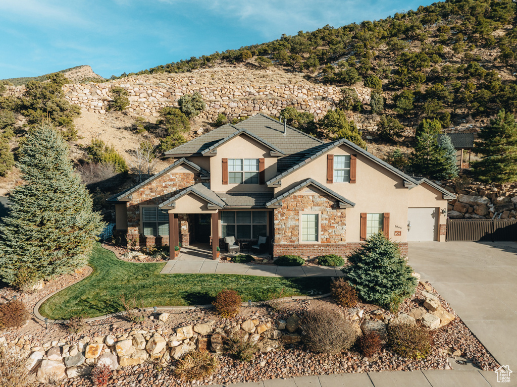 View of front of house featuring stucco siding, driveway, stone siding, and an attached garage