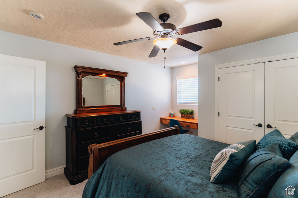 Bedroom featuring light carpet, a closet, a ceiling fan, and baseboards