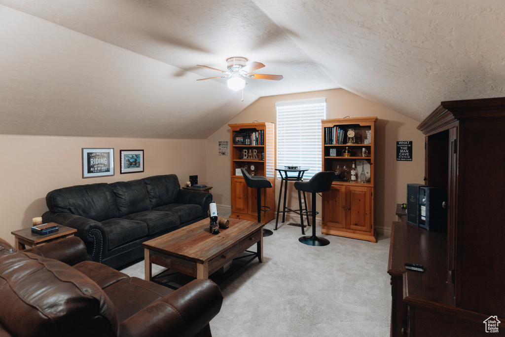 Living room featuring light colored carpet, lofted ceiling, ceiling fan, and a textured ceiling
