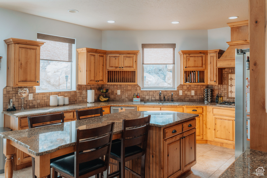 Kitchen with a sink, plenty of natural light, decorative backsplash, a breakfast bar, and recessed lighting