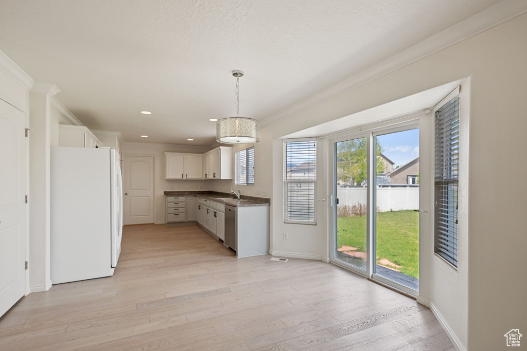 Kitchen with freestanding refrigerator, ornamental molding, dishwasher, dark countertops, and light wood-type flooring