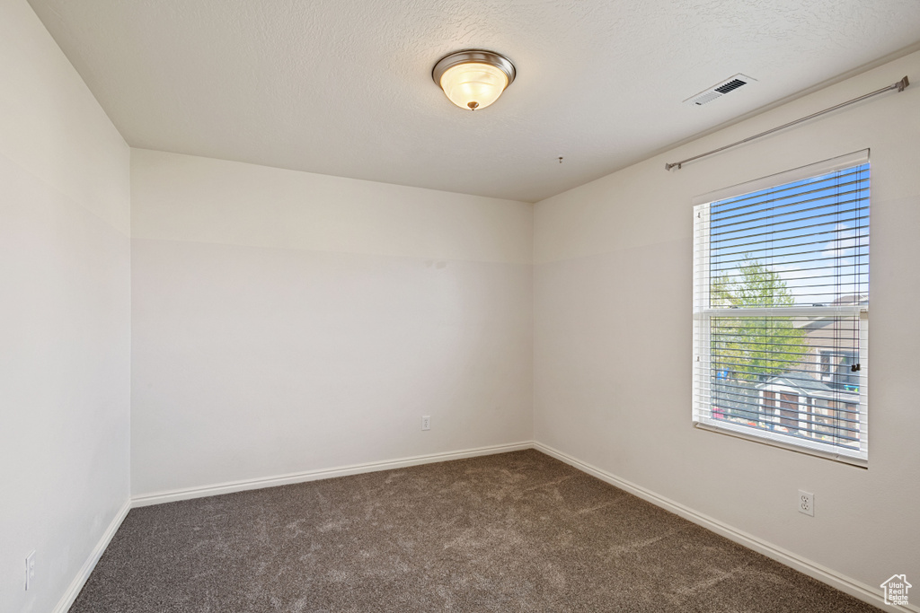 Unfurnished room featuring dark colored carpet and baseboards