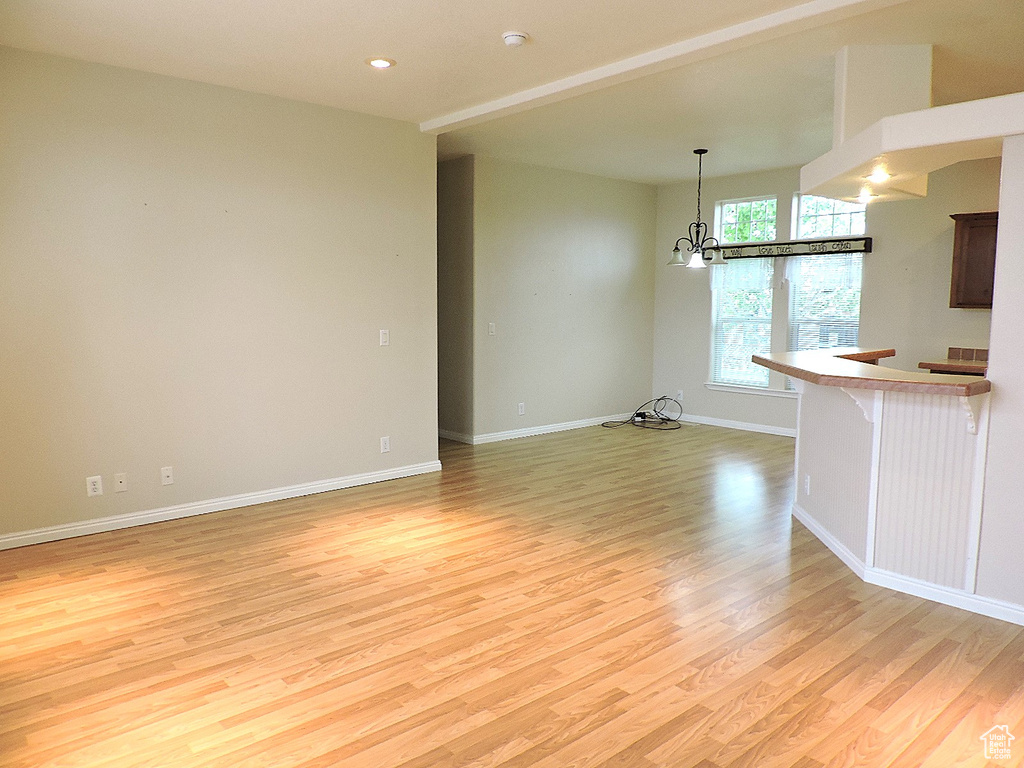 Unfurnished room featuring light wood-style floors, a chandelier, baseboards, and recessed lighting