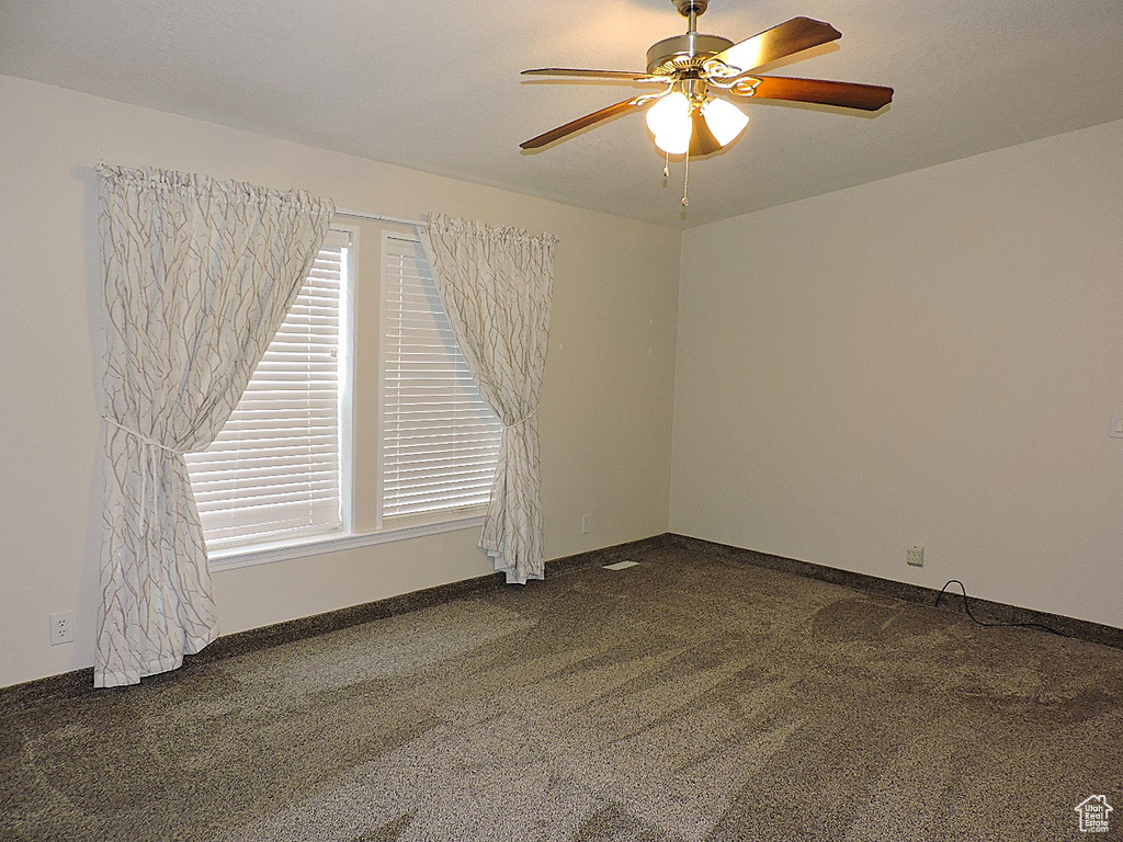 Carpeted spare room with ceiling fan and baseboards