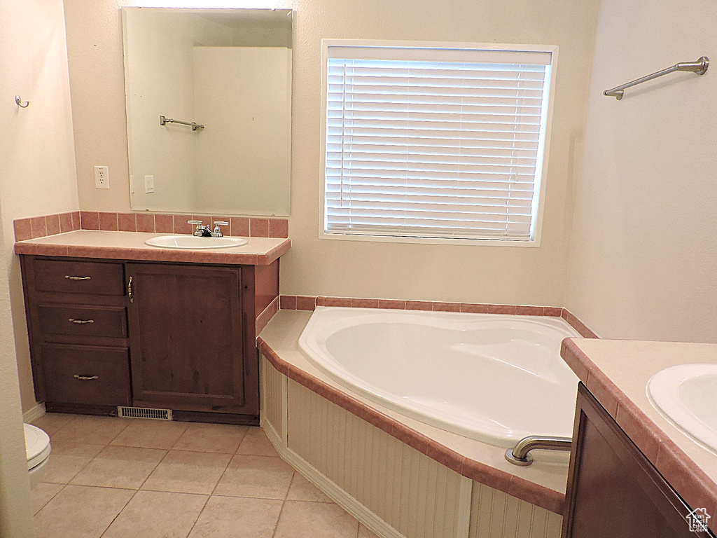 Bathroom with two vanities, a bath, tile patterned flooring, and toilet