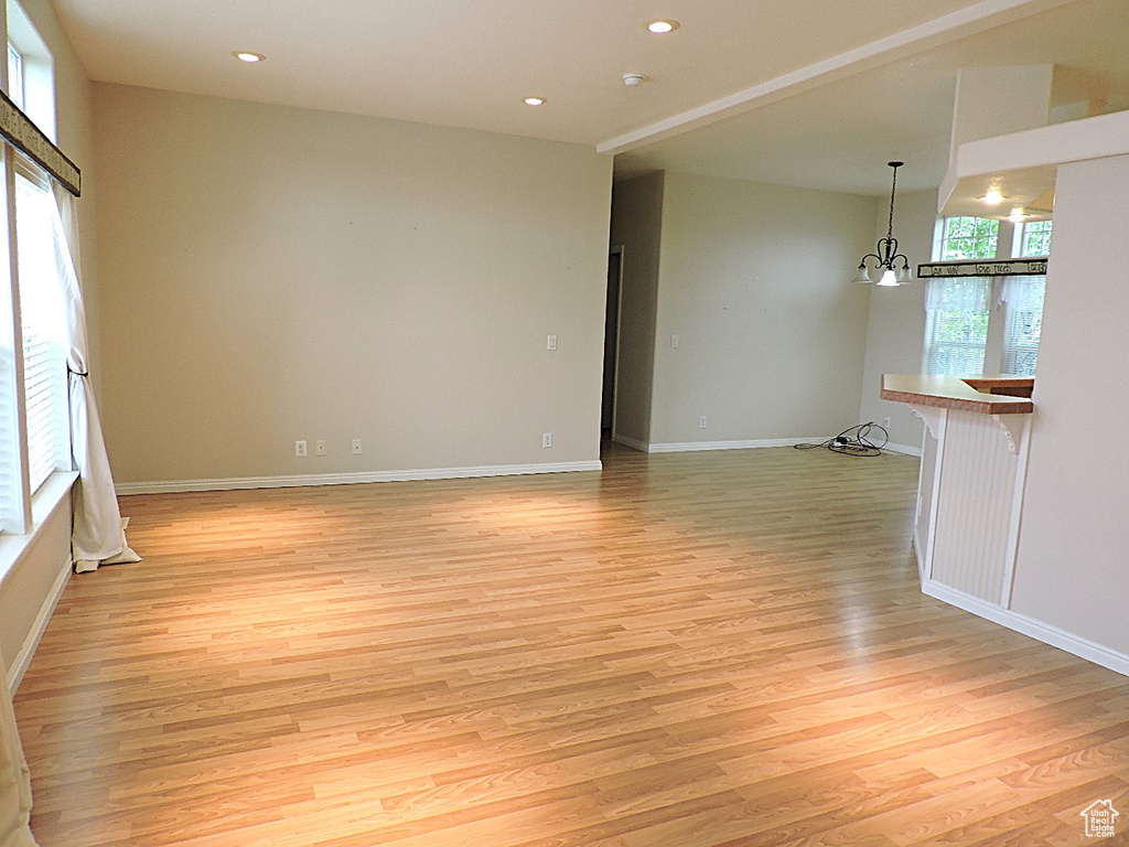 Spare room with light wood finished floors, a chandelier, recessed lighting, and baseboards