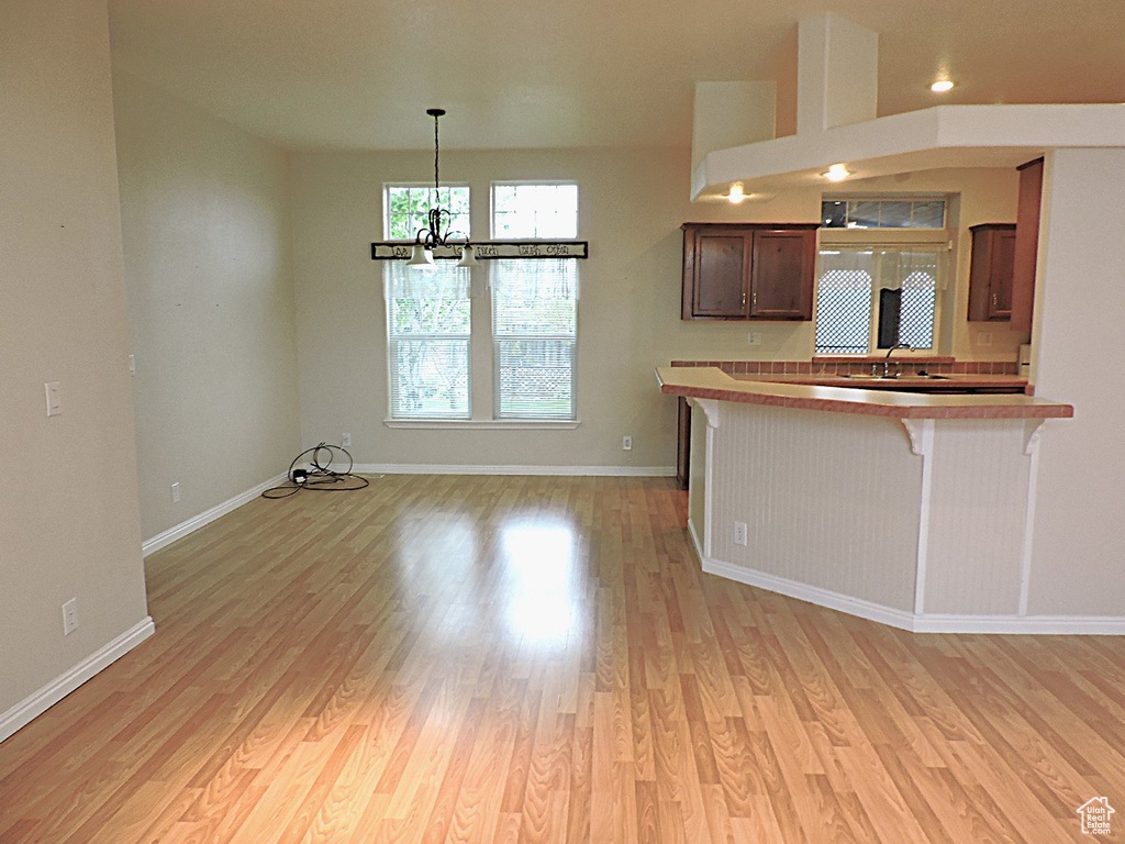 Kitchen with a kitchen breakfast bar, light wood-style flooring, baseboards, a chandelier, and pendant lighting