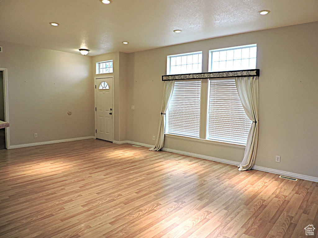 Unfurnished living room featuring wood finished floors, baseboards, and recessed lighting