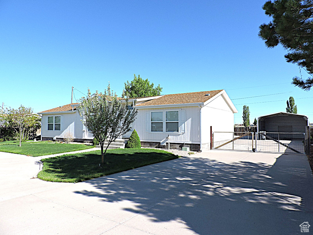 View of front of house featuring a gate, driveway, and a detached carport