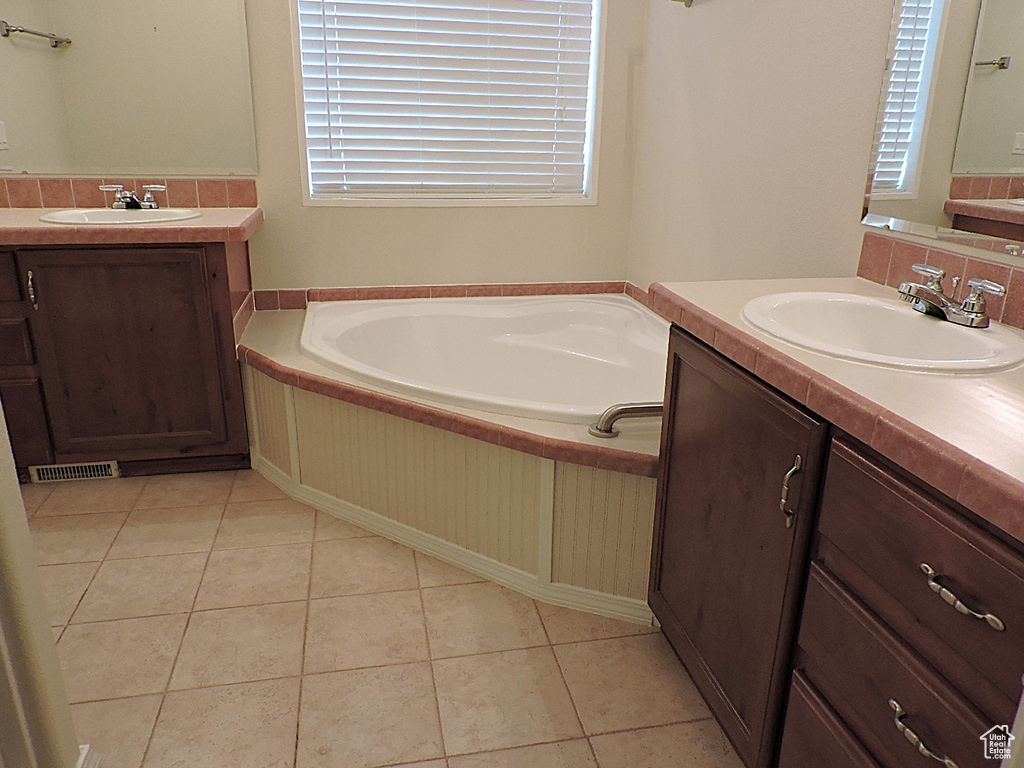 Full bathroom with plenty of natural light, two vanities, and a garden tub