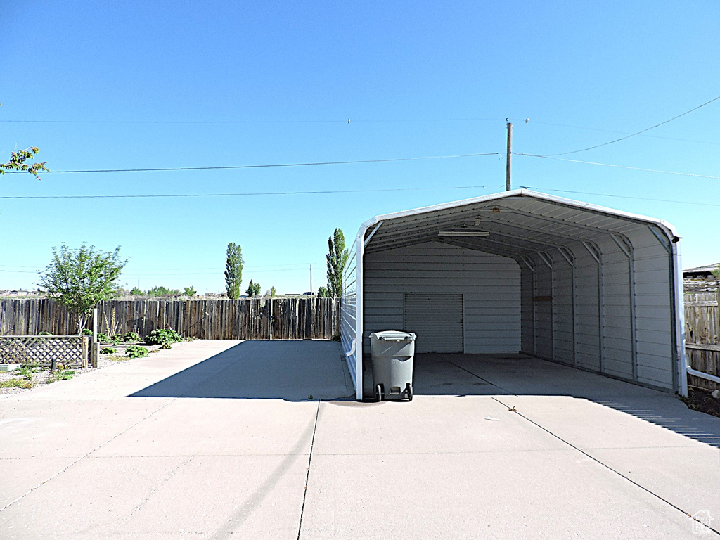 Garage with fence, a carport, and concrete driveway