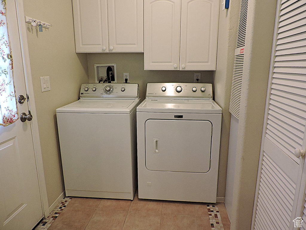 Washroom with washer and dryer, cabinet space, and light tile patterned floors
