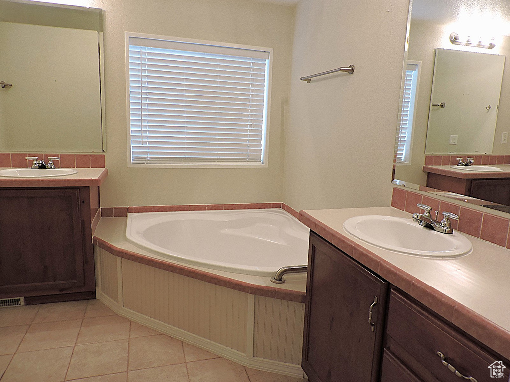 Full bath featuring plenty of natural light, two vanities, and a bath